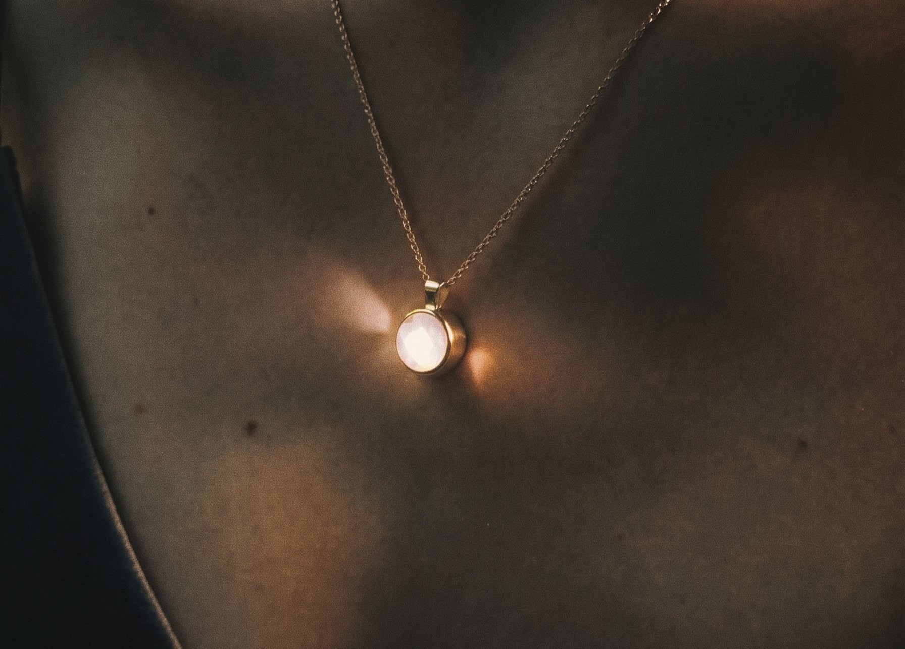 Louis Jacques self-illuminating sterling silver necklace glowing in close-up on model’s neckline.